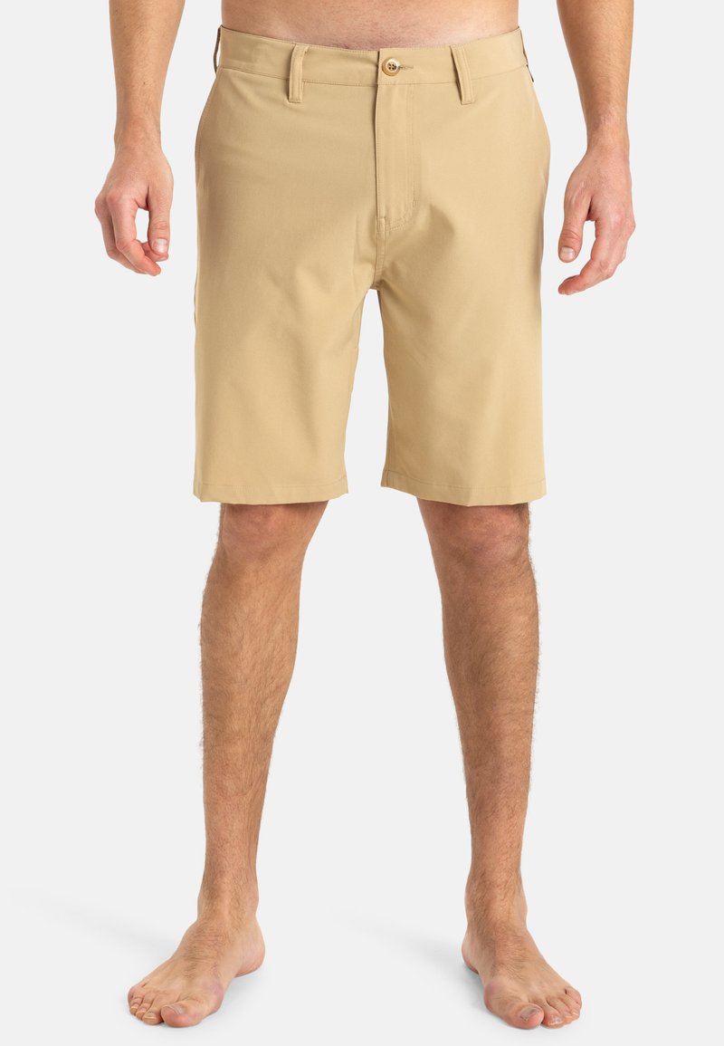 Shorts beiges en tissu lisse, dotés d'une fermeture à boutons, de passants de ceinture et de poches latérales, avec une coupe droite. Pas de motifs.