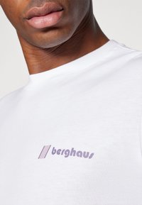 Biely bavlnený tričko s levanduľovým logom "berghaus" na prednej strane, okrúhlym výstrihom, krátkymi rukávmi a hladkou textúrou.