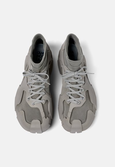Sneaker grigi con tomaia in rete testurizzata, sovrapposizioni in gomma, lacci e un design modellato unico, dotati di un collare imbottito per il comfort.