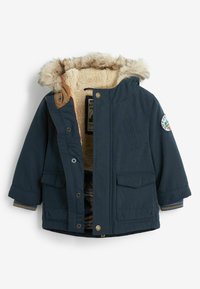 Manteau d'hiver bleu marine pour enfants avec capuche en fausse fourrure, doublure en polaire beige, fermeture par boutons et fermeture éclair, et écusson sur la manche gauche.