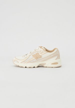 Lightweight running shoe in white mesh and beige synthetic materials, featuring a padded collar, laces, and a textured rubber sole.