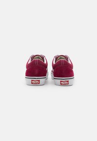 Burgunderfargede semskede sneakers med hvite gummisåler. Merkbare hvite sømmer og en rød "Vans Off the Wall" logo på hælen. K klassisk lavtoppdesign.