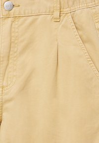 Jasnożółte bawełniane spodnie o gładkiej fakturze, z przodu plisy, bocznymi kieszeniami i metalowym guzikiem w talii.