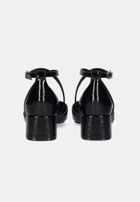 Sandalias de tacón bloque de charol negro con tiras entrelazadas, correa en el tobillo y un detalle texturizado en el tacón, mostradas desde la vista trasera.