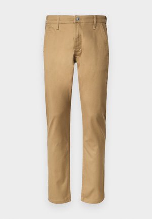 Beige chinos, egyenes szárú vágással. Pamutból készült, elöl gombos záródással, övhurkokkal és oldalsó zsebekkel rendelkezik. Sima textúrájú.