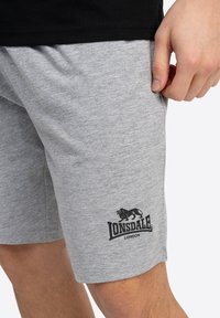 Pilki medvilniniai šortai su elastinga juosta, šoninėmis kišenėmis ir juodu liūto logotipu bei užrašu "Lonsdale London" kairiajame šone.