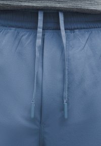 Heled sinine spordipüksid elastse vöökohaga, millel on sobivad nöörid ja sile ning pehme tekstuur.