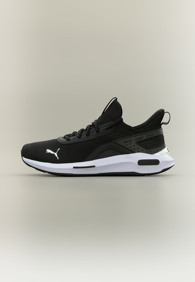 Αθλητικό παπούτσι Puma σε ασπρόμαυρο με πλεκτό επάνω μέρος, κλείσιμο με κορδόνια και επενδεδυμένη σόλα, εμφανίζεται από το πλάι σε ουδέτερο φόντο.