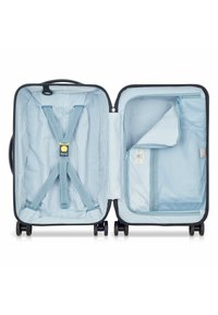 Valise rigide de couleur sombre, non zippée. L'intérieur présente un tissu rayé bleu, des sangles élastiques et une poche en mesh pour l'organisation.