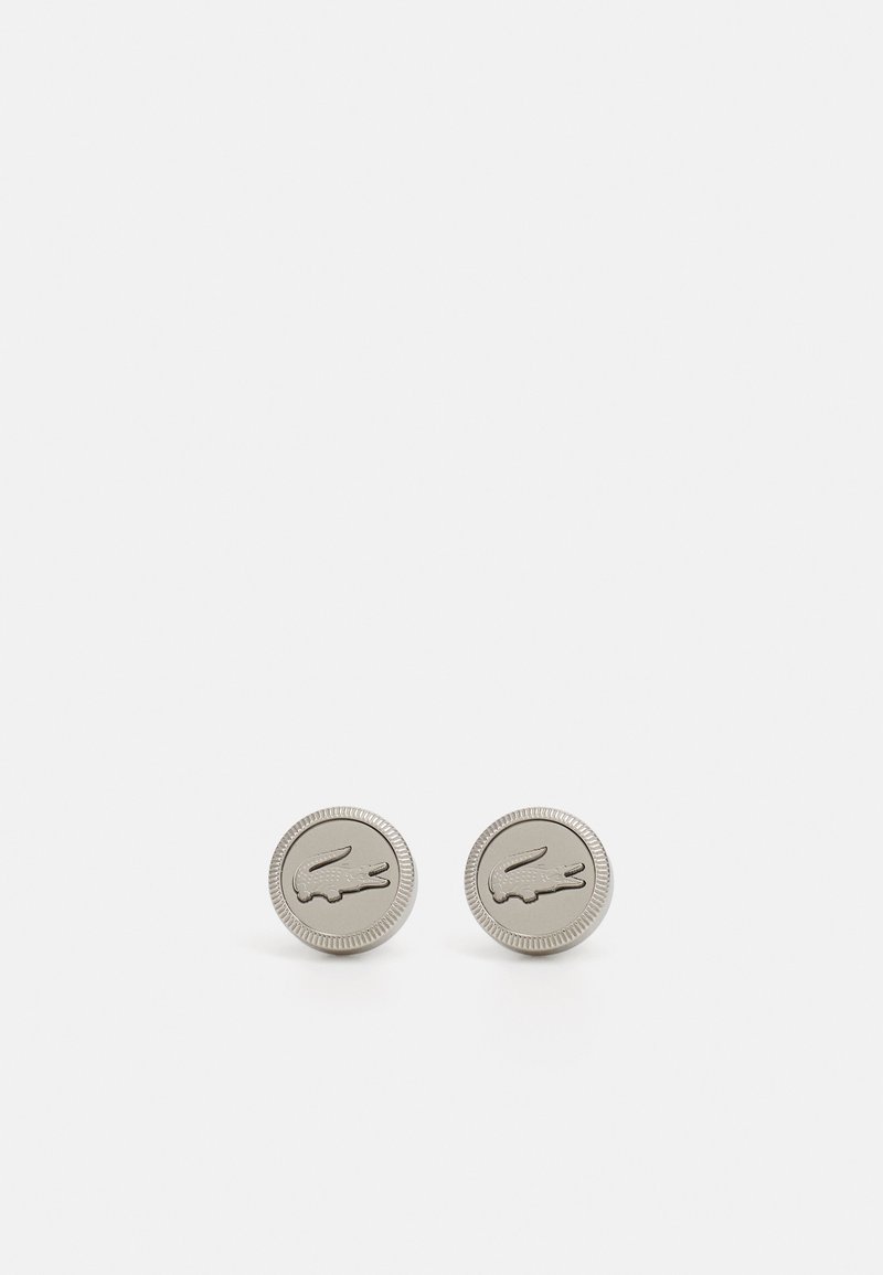 Sølvfarget metall cufflinks med sirkulær form, med en hevet krokodille-logo og teksturert kantdetalj.