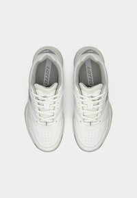 Λευκά αθλητικά παπούτσια με ανώτερο μέρος από λείο δέρμα, διάτρητες λεπτομέρειες και γκρι πινελιές. Διαθέτουν επίπεδα κορδόνια και αναπαυτική σόλα. Ορατό το λογότυπο.