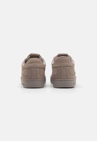 Brune semskede sneakers med lavt design, polstret krave og enkle stikninger. Gummisåler for grep og holdbarhet.
