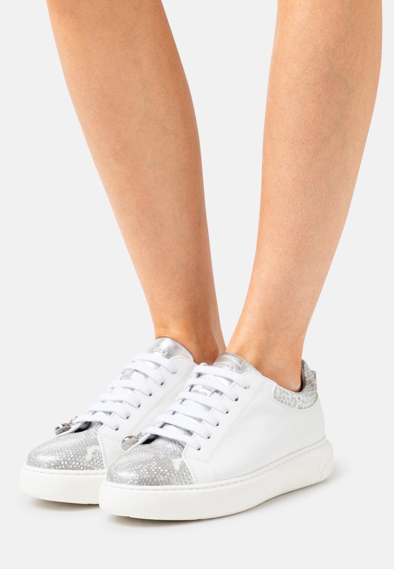 Sneaker bianchi con un accento testurizzato argento sulla punta e sul tallone; design con lacci; materiale liscia e suola in gomma.