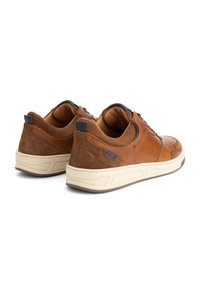 Een paar casual sneakers van bruin leer en suede met dikke witte zolen, veters en een gevoerde binnenvoering, van achter gezien op een witte achtergrond.