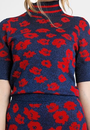 Granatowy dzianinowy komplet: top i spódnica z jaskrawoczerwonym kwiatowym wzorem, krótkie rękawy oraz wysoki dekolt z czerwono-czarnymi paskami.