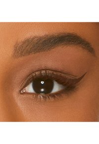 Close-up van een donkerbruine oog met een duidelijke zwarte eyeliner vleugel, omringd door textuurrijke, donkere wenkbrauwen en een zachte huid.