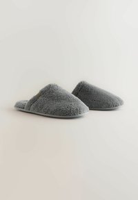 Gray fuzzy slippers with a textured exterior, rounded shape, low sides, and soft lining. Features a flat gray sole for indoor use.