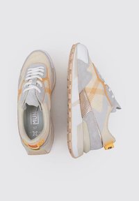 Zapatillas gris claro y beige con materiales de malla y ante, acentos naranjas, cordones blancos, suela texturizada y una etiqueta en la parte posterior.