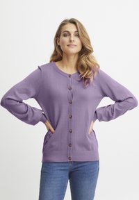 Ljubičasti pleteni kardigan s okruglim izrezom, prednjim zatvaranjem na gumbe i bočnim džepovima. Ima rebraste manžete i rub, glatku teksturu.