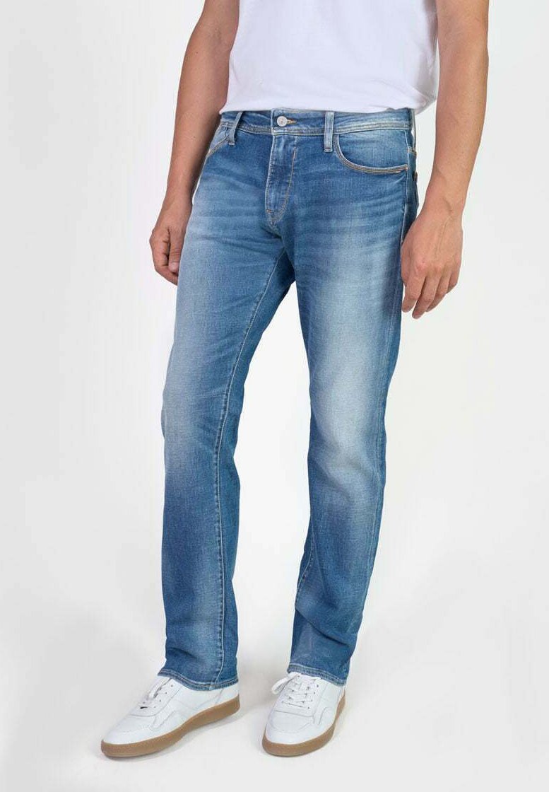 Jeans de color azul claro con corte recto, hechos de denim. Presentan un ligero desgaste, diseño de cinco bolsillos y cierre con cremallera. Combinados con zapatillas blancas.