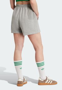 Grå bomullsshorts med elastisk midja, tillsammans med vita knästrumpor med gröna ränder och bruna skor.