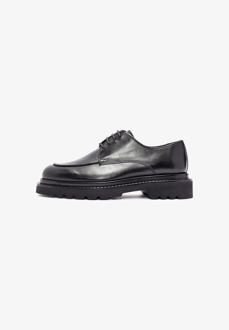 Schwarze Leder-Schuhe mit einem schlanken Design, runder Zehenpartie und fünf Ösen. Verfügt über eine strukturierte, voluminöse Gummisohle und weiße Nahtakzente.