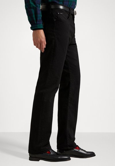 Black denim jeans with a straight cut, paired with black shoes featuring red accents. The jeans have a clean design and standard waistline.