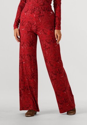 Rode wijde broek met bloemenpatroon, elastische tailleband en zachte stof, gecombineerd met bruine slideschoenen.