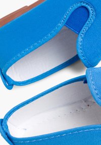 Blauwe stoffen instapschoenen met een gladde binnenvoering en rubberen zool. Beschikt over een gebogen uitsnijdingontwerp bij de hiel.