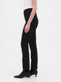 Črne skinny jeans hlače z visokim pasom, narejene iz denima. Imajo zadnje žepe in obliko ožjih nog. Nosijo se z črnimi petkami.