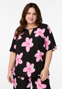 Czarna bluzka z krótkimi rękawami, ozdobiona dużymi różowymi wzorami kwiatowymi, z dekoltem w kształcie łezki oraz luźnym krojem. Gładka tekstura materiału.