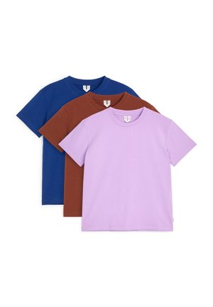 Trois t-shirts unis à manches courtes empilés dans les couleurs lavande, marron et bleu foncé avec des encolures rondes et des étiquettes visibles.