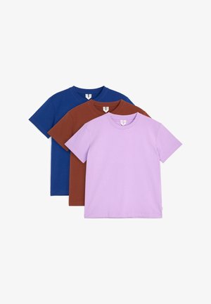 Trois t-shirts unis à manches courtes empilés dans les couleurs lavande, marron et bleu foncé avec des encolures rondes et des étiquettes visibles.