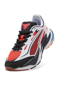 Sneaker Puma RS bianca, nera e rossa con pannelli in rete, lacci neri e un accento blu sulla suola intermedia, inclinata per mostrare la parte anteriore e laterale.