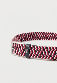 Spleciony pasek w kolorach czerwonym, białym i granatowym, z prostokątną srebrną klamrą i czarną pętlą z małym emblematem flagi.