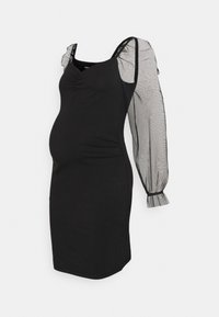 Vestido de maternidade preto com uma silhueta ajustada, apresentando mangas bufantes transparentes e detalhes acolchoados à frente para um efeito texturizado.