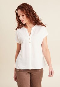 Witte blouse met korte mouwen, V-hals en twee zichtbare knopen. Zacht stof met een iets losse pasvorm, uitgevoerd in een effen kleur zonder patronen.