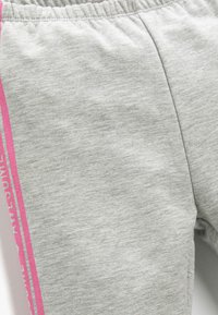 Graue Baumwoll-Sweatpants mit elastischem Bund, die einen rosa Streifen entlang der Seite und einen strukturierten Stoff mit melierter Optik aufweisen.