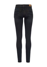 Jean skinny bleu foncé vu de dos avec deux poches arrière et une étiquette de marque marron sur la ceinture.