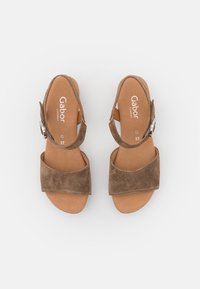 Bruna mockaskor med bred framslitsrem och ankelspänne, med en slät innersula och logotyp i vitt. Storlek 37.