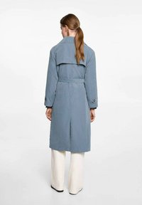 Svietlo modrý trenčkot s opaskom v páse, veľkým golierom a zadným rozparkom. Dlhé rukávy s gombíkovými detailmi, vyrobený z mäkkého materiálu.