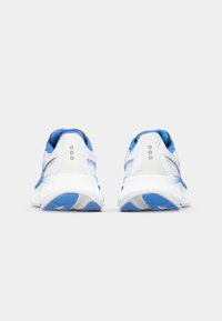 Baskets de sport blanches et bleues avec une tige en mesh, semelle rembourrée et talon renforcé. Présente un logo sur le talon et des accents de design texturé.
