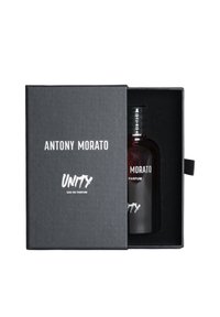 Caja texturizada negra con texto de logotipo en blanco, que contiene una botella de vidrio oscura en su interior con la etiqueta "UNITY Eau de Parfum" y un tapón negro.