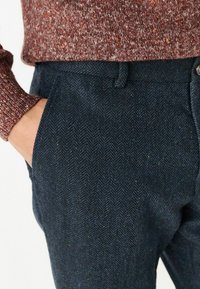 Námořnické herringbone kalhoty s texturovanou tkaninou. Mají standardní pas, boční kapsy a jemný barevný skvrnitý vzor.