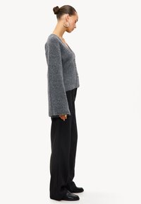 Grijze wollen cardigan met een V-hals, drie knopen en wijde mouwen, gecombineerd met zwarte broek en platte schoenen. Glad textuur, casual pasvorm.