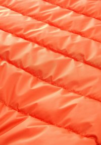 Orangener gestepptes Gewebe mit vertikalen Nahtreihen, glatter Textur und leichtem, plüschigem Aussehen.