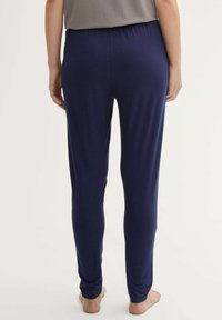 Pantaloni allungati di un blu scuro, elasticizzati, con una struttura morbida e una vita elastica, caratterizzati da una vestibilità slim che si stringe alle caviglie; senza ulteriori dettagli.