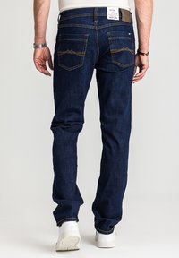 Ciemnoniebieskie dżinsy z denimu o prostym kroju, wyposażone w dwie tylne kieszenie z przeszyciami w kształcie gór oraz materiałową metkę na pasie.