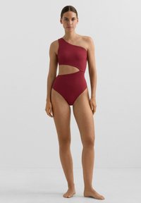 Ena delovna kopalke malinaste barve z teksturirano obdelavo, z asimetričnim ramenom, izrezom v pasu in visokim izrezom na nogah.