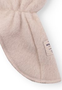 Cappello in pile beige chiaro con texture morbida, parte superiore arricciata e bordi cuciti. Presenta un'etichetta con il nome del marchio e dettagli sul lato.
